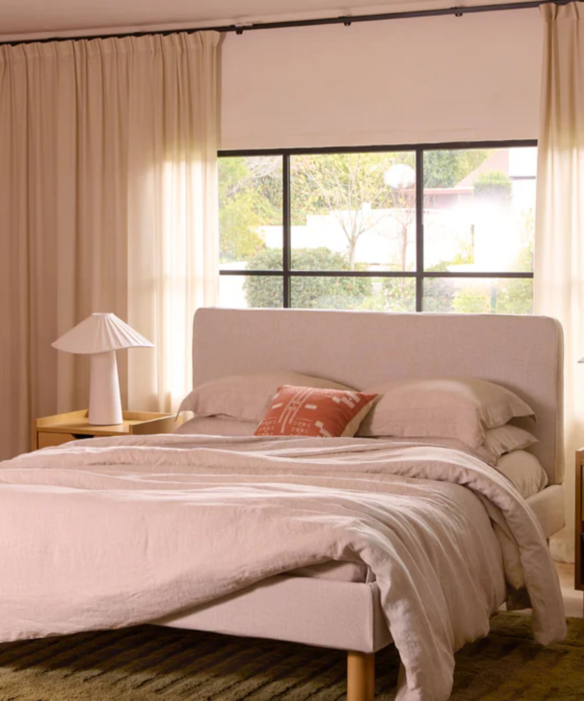 neutral modern bedroom with high ceiling linen drapes and a natural upholstered bed
