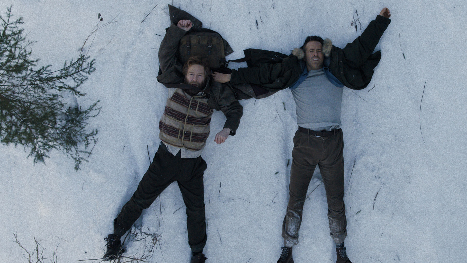 Kenneth Branagh and Ryan Reynolds lie in the snow in Apple TV's Mayday