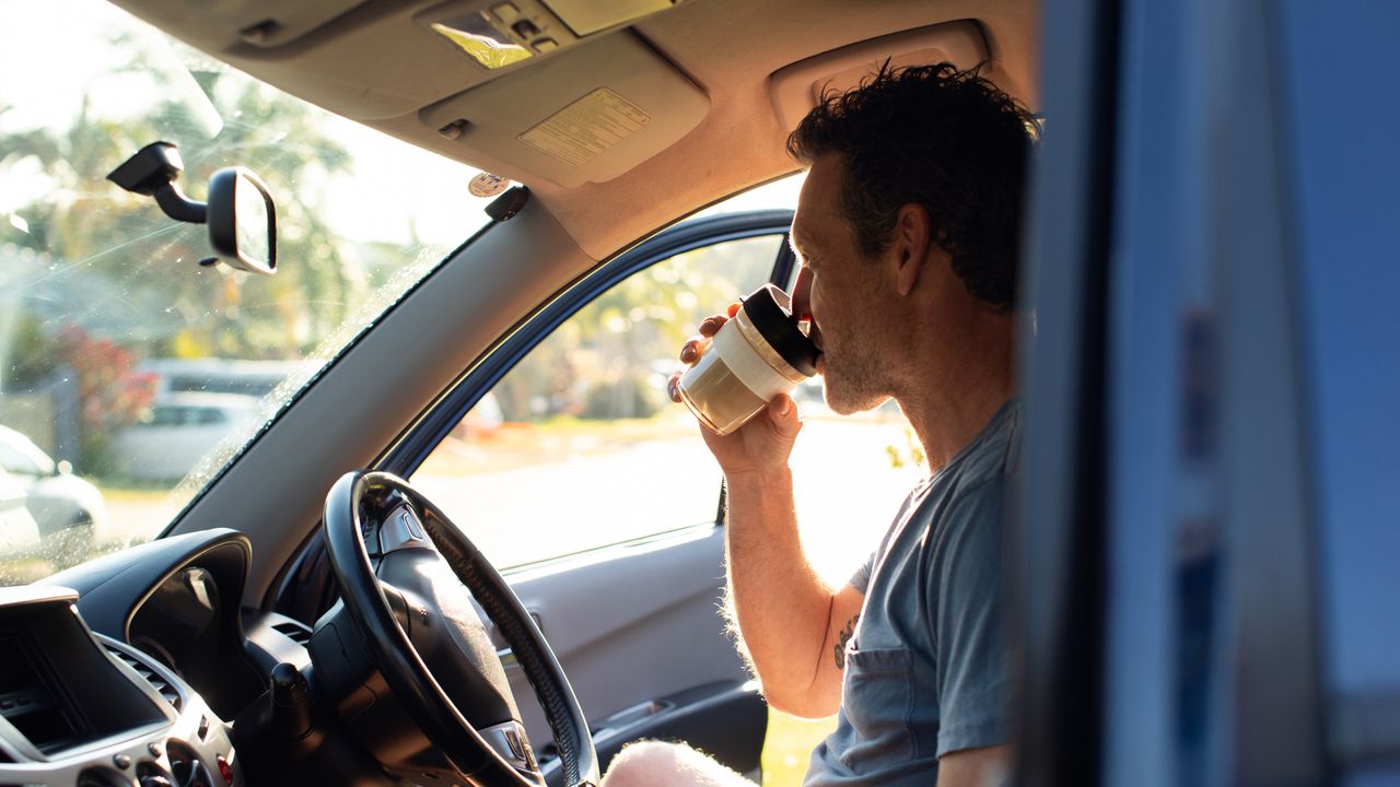 Man having his morning coffee on the move after waking up at 5am