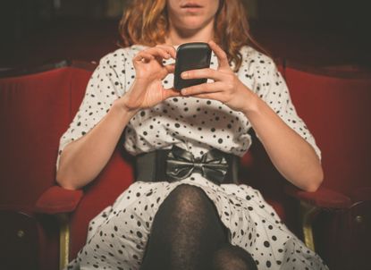 Woman using phone in theater.