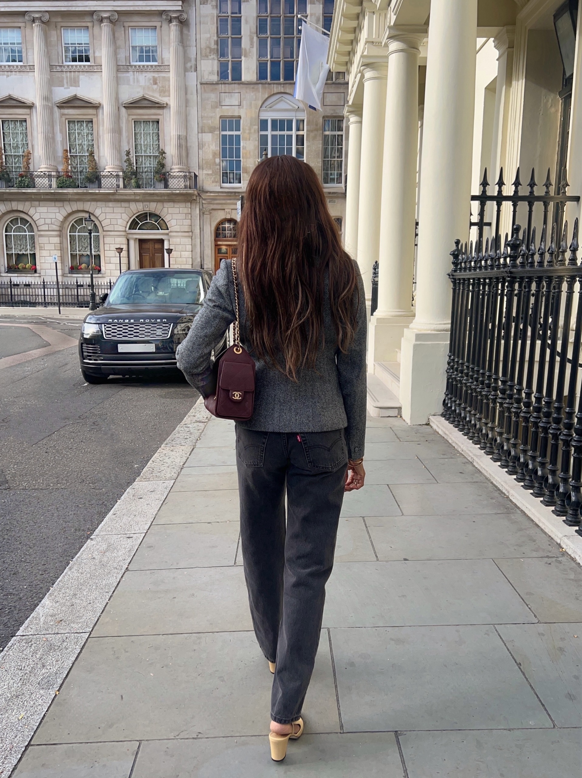 Influencer @symphonyofsilk wears grey jeans with a grey knit, a burgundy back and beige shoes.