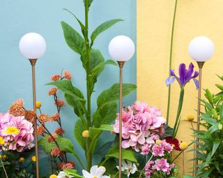stake globe lights in flowerbed with painted garden walls