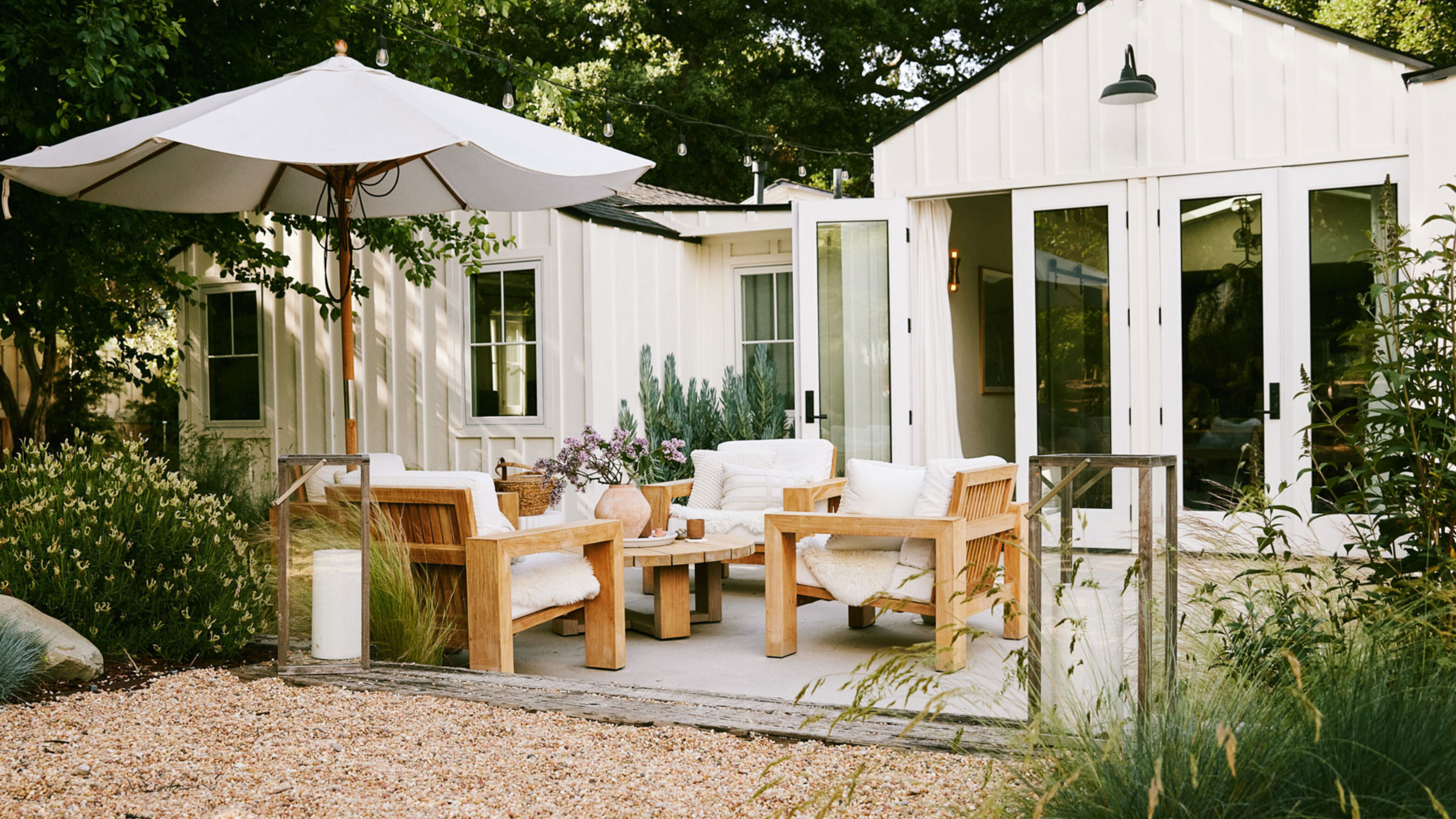 deck with garden furniture and umbrella, gravel landscaping and ornamental grasses