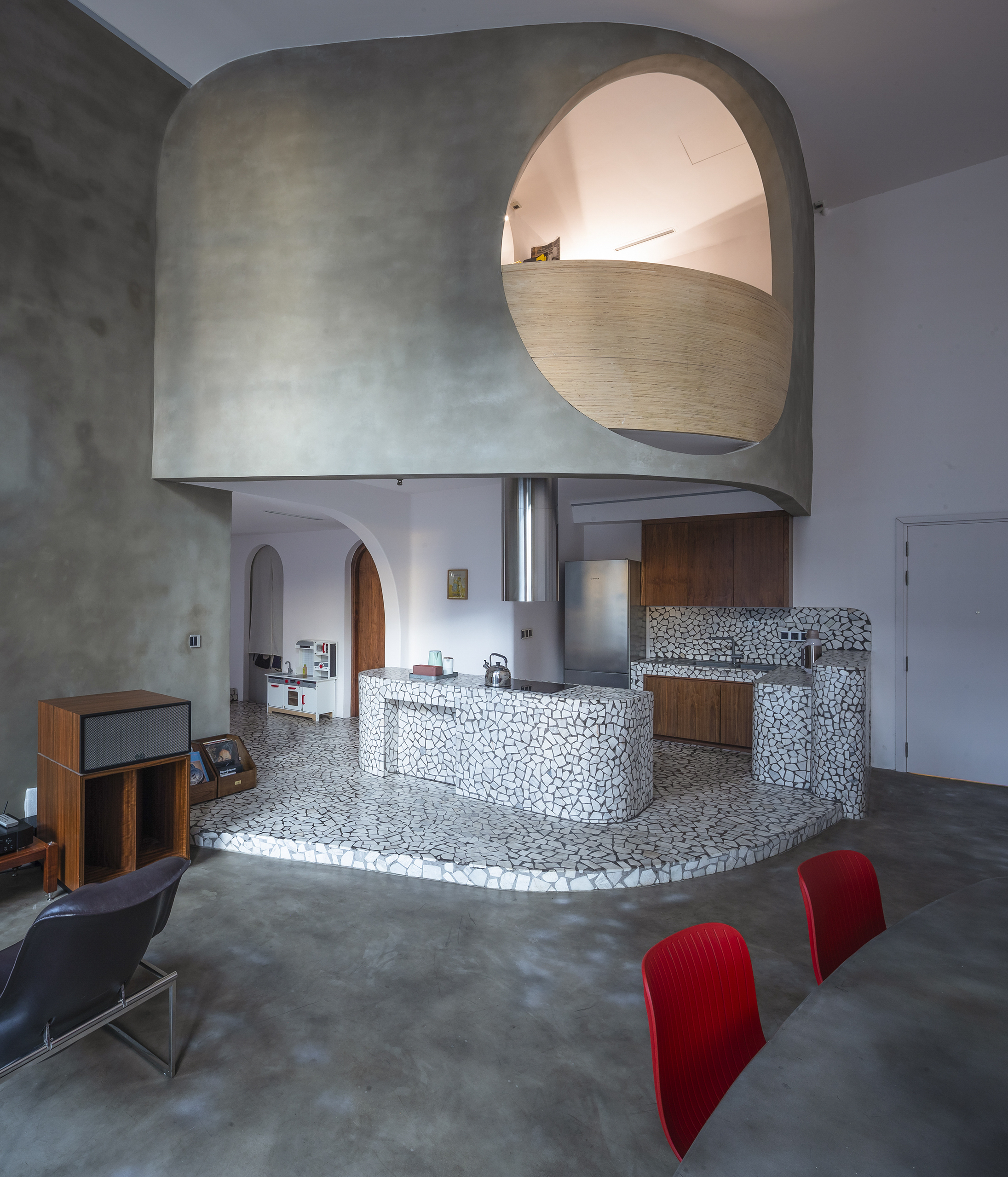 A kitchen designed entirely in terrazzo with a dining table that has red chairs