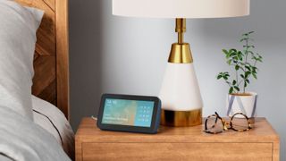 Amazon Echo Show 5 on bedside table beside white and gold lamp