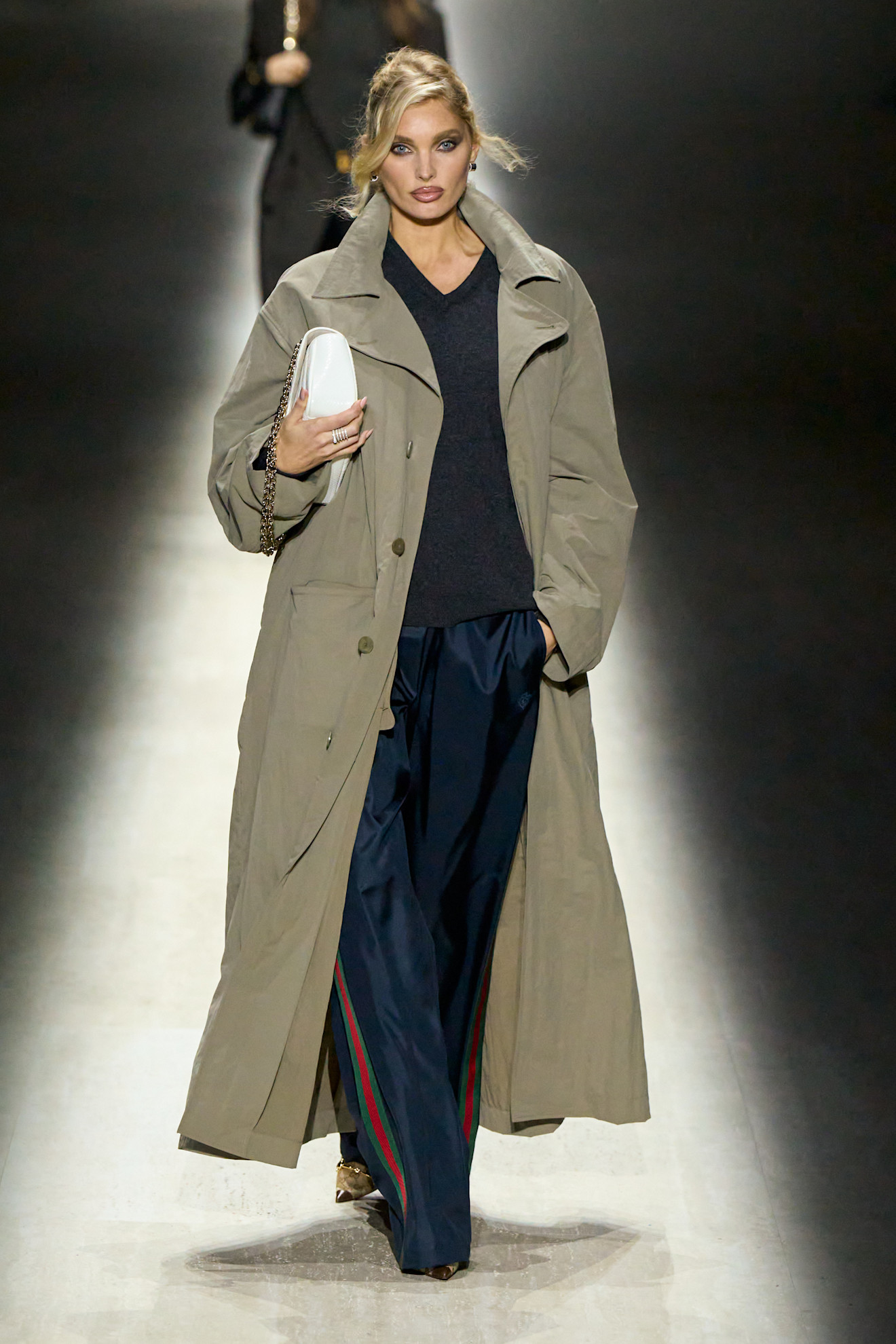 Elsa Hosk walking in the Gucci F/W 26 show wearing a trench coat and track pants.
