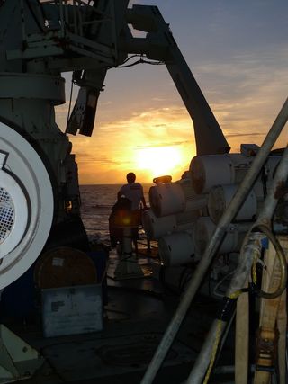 A scientist at sunset on a research vessel.