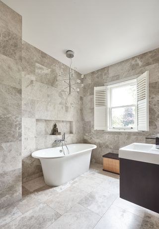 bathroom with large format tiles, freestanding bath and a chandelier