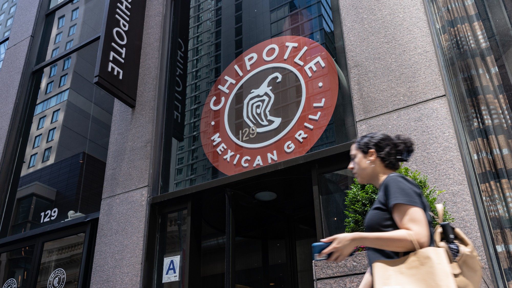 A woman walks past a Chipotle restaurant in New York City. 