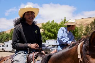 A young man on a horse wearing a cowboy hat at the rodeo