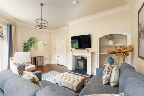 A living room with a corner sofa and TV hanging above a wood burning stove