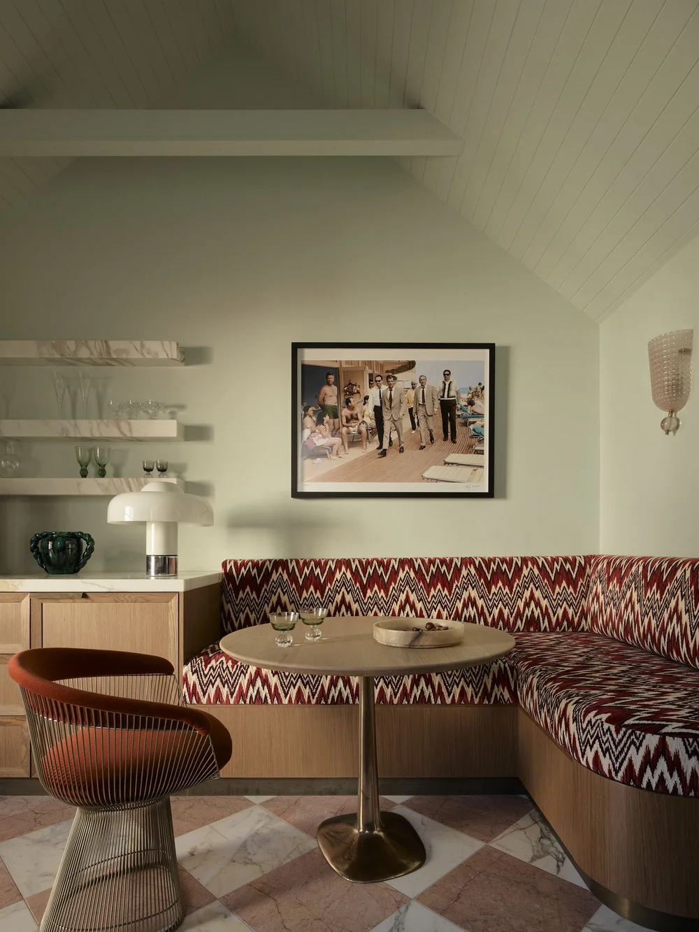 Corner banquette seating in abstract zig-zag velvet with round table and checkerboard marble floor