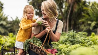 Happy mom picking fresh vegetables with her daughter