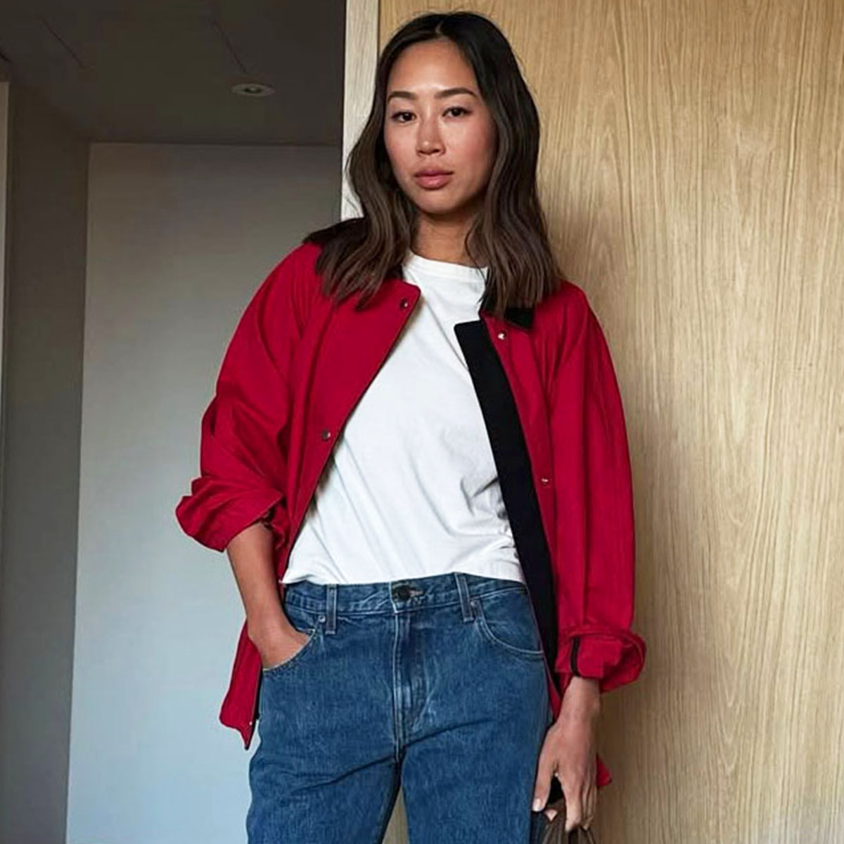Woman in a red jacket, white t-shirt, and jeans