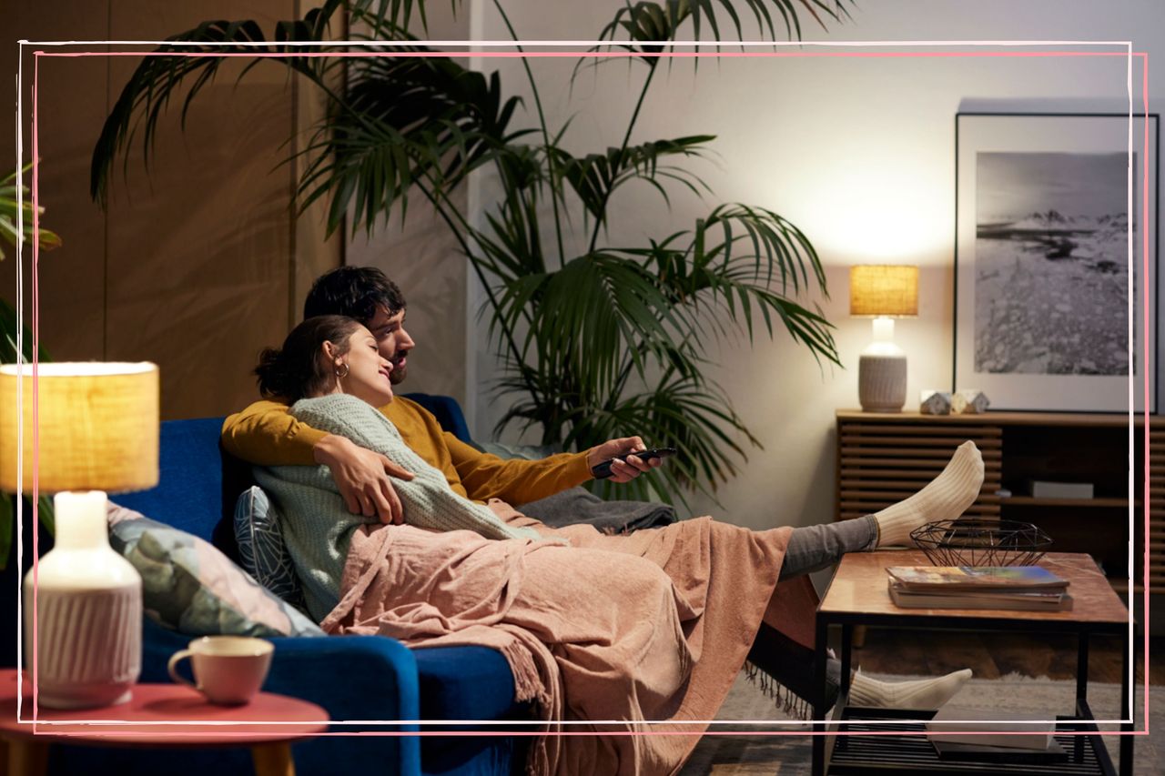 A couple hugging on a sofa while watching TV