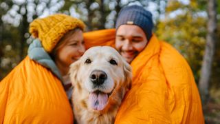 Couple and dog wrapped up in sleeping bag