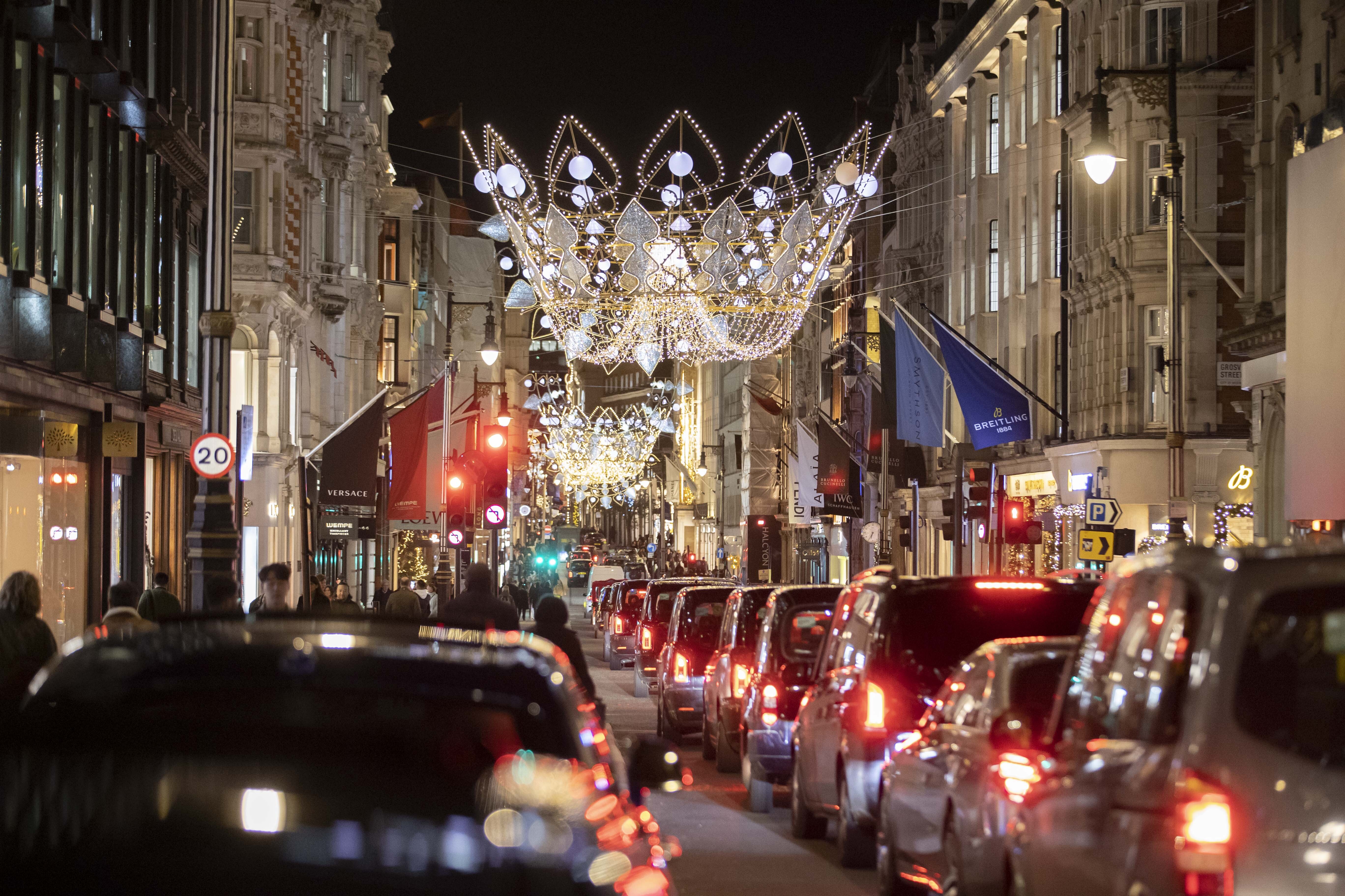 Black cabs and cars stuck in traffic down Bond Street which is illuminated by giant Christmas lights in the shape of crowns