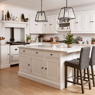 a traditional white kitchen with shaker-style cabinetry and a large square island and breakfast bar