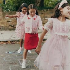 3 girls playing hopscotch wearing pink and red dresses with heart detailing