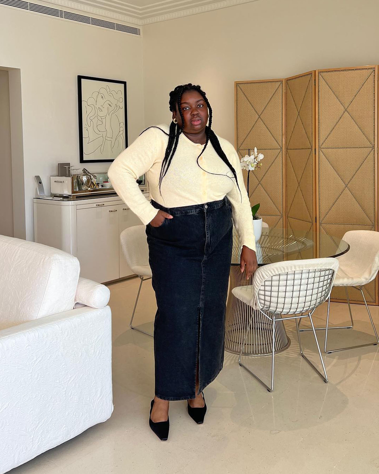 British influencer Abisola Omole poses in a lightweight knit, denim maxi skirt, and slingback kitten heels