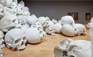 large human like skulls stacked in a display and rolling away in an art gallery