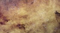 a dense field of glowing stars with cloudy wisps of gas scattered throughout