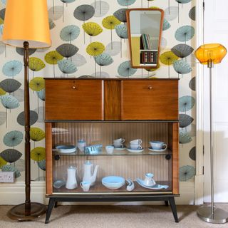 A hallway with a display cabinet and bold wallpaper
