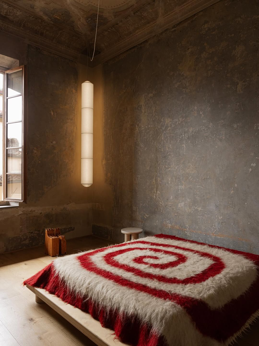 Red and white throw with swirling pattern shown on bed, designed by Grace Atkinson