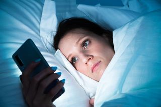 A women in bed checking her phone before going to sleeep