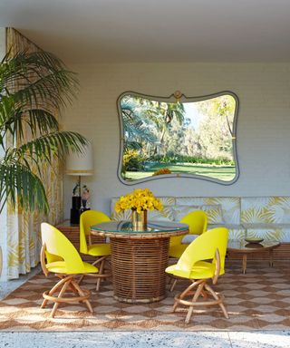 Dining room with yellow chairs, a wicker table and a large checked rug