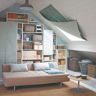 An attic room with organised storage that doubles as a guest room with a beige sofa bed