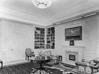 The library of Clarence House in London, 1949. The house was built in 1825-27 by John Nash for the Duke of Clarence, later King William IV. The painting above the fireplace is the HMS Vanguar