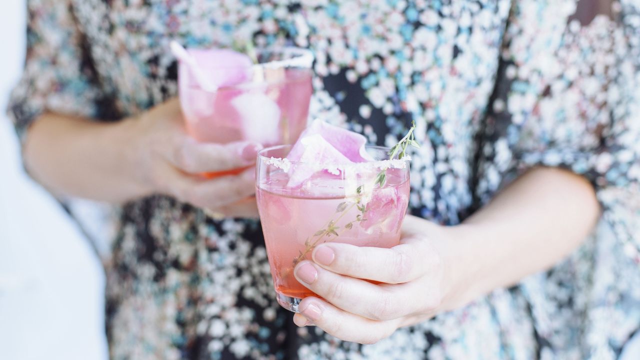 Woman holding two cocktails.