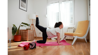Woman doing donkey kick exercise on a yoga mat at home