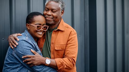 A young woman hugs her father as they both smile.