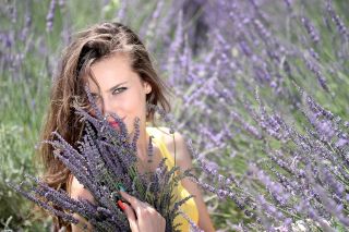 A woman posing among lavender flowers.