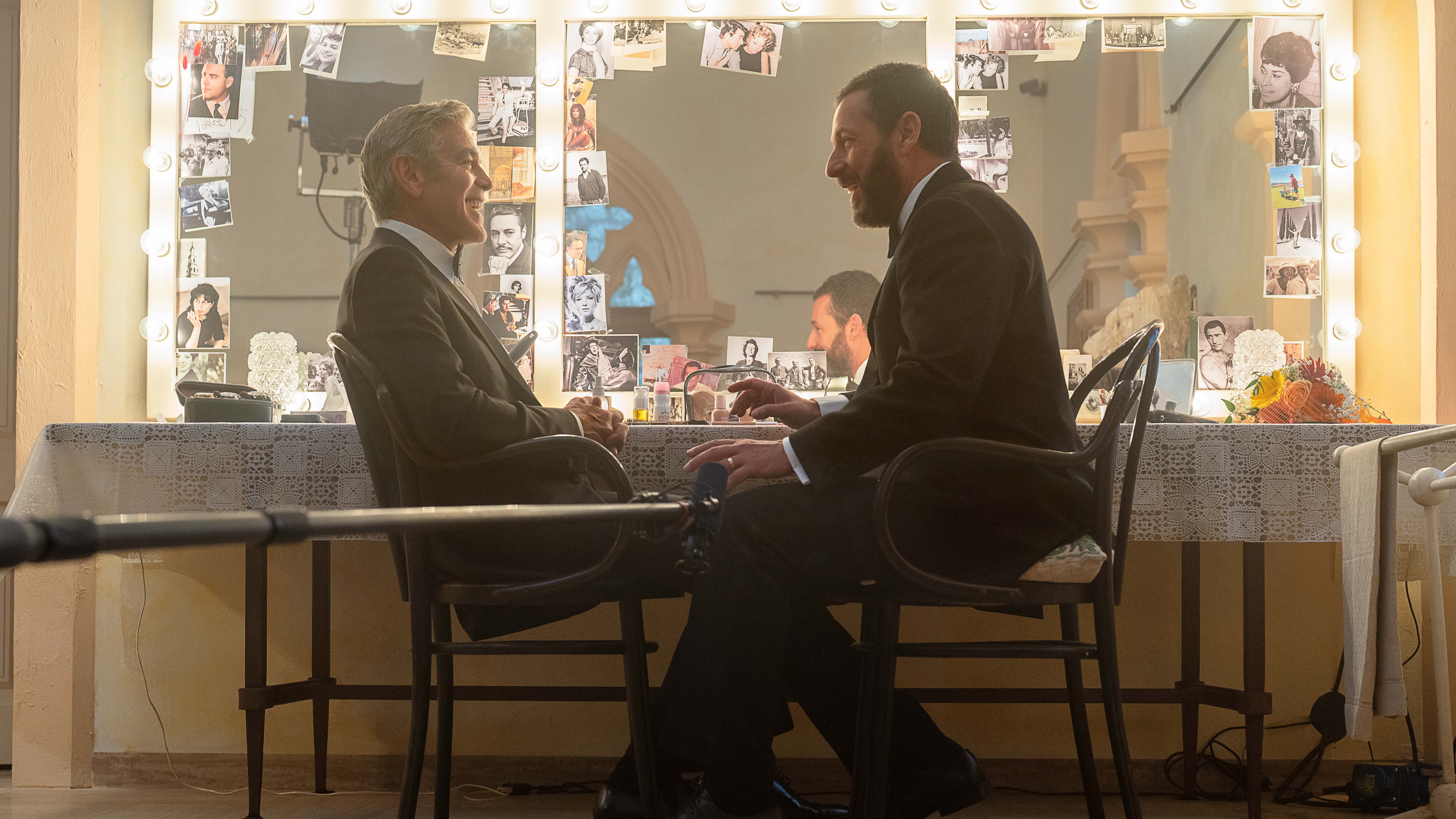L-R: Jay Kelly (George Clooney) and Ron Sukenick (Adam Sandler) sit opposite one another on-set of Netflix's "Jay Kelly"