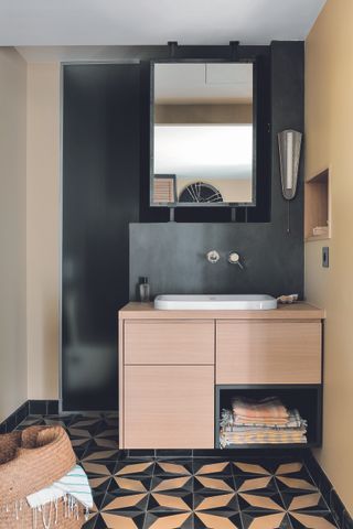 A bathroom with black walls and a wooden vanity