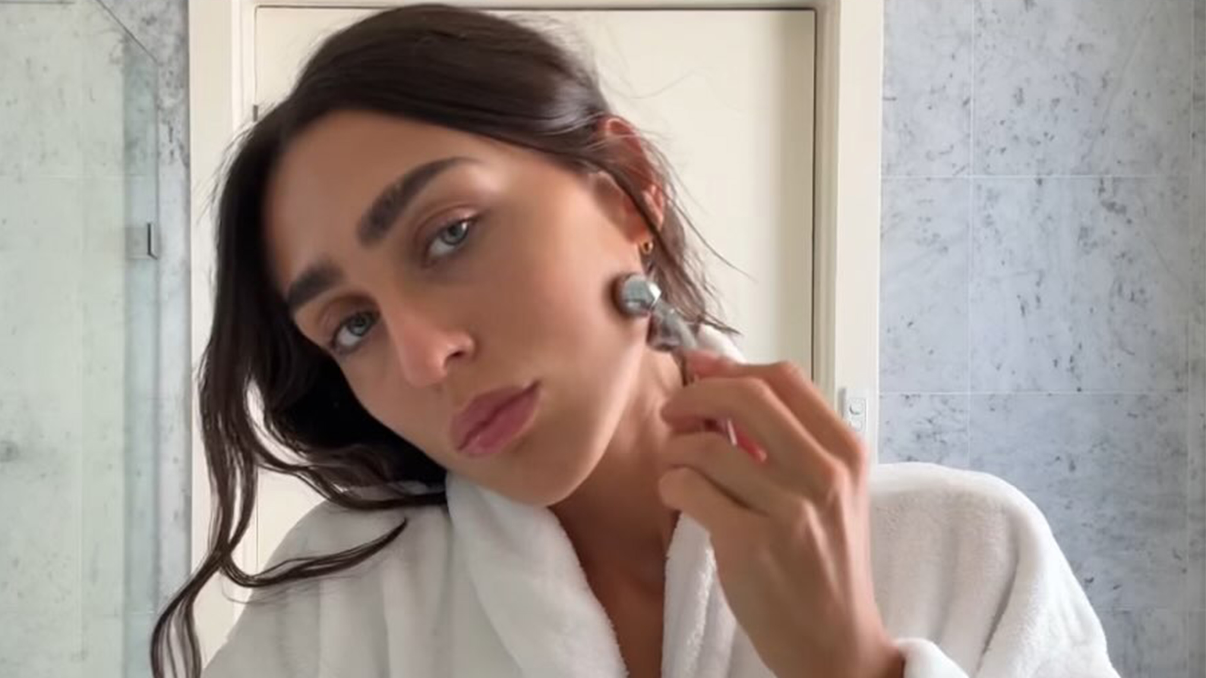 Camelia Farhoodi using a face massage beauty tool.