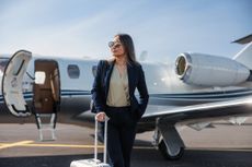 Confident businesswoman standing by a private jet, ready for luxurious travel.