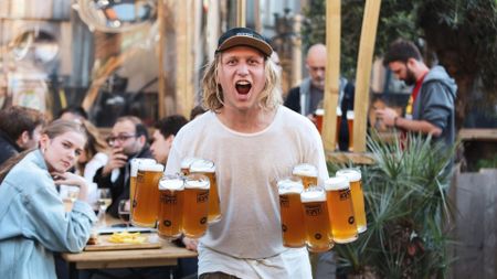 A man holding 11 pints of beer. 