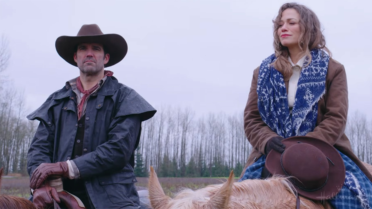 Bethany Joy Lenz and Benjamin Ayres both ride horses in full cowboy gear in a field in Langley, BC for Hope Valley: 1874.