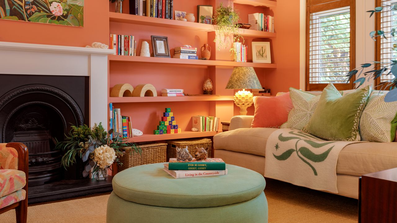 Warm toned living room colour scheme with greens and orange-pinks, pouffes, sofa, and shelving