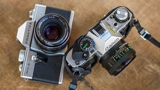 Praktica MTL5 and Canon AE-1 35mm SLR cameras on a table