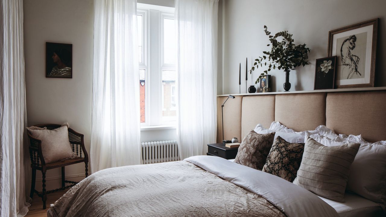 Neutral painted bedroom with large windows and sheer white curtains