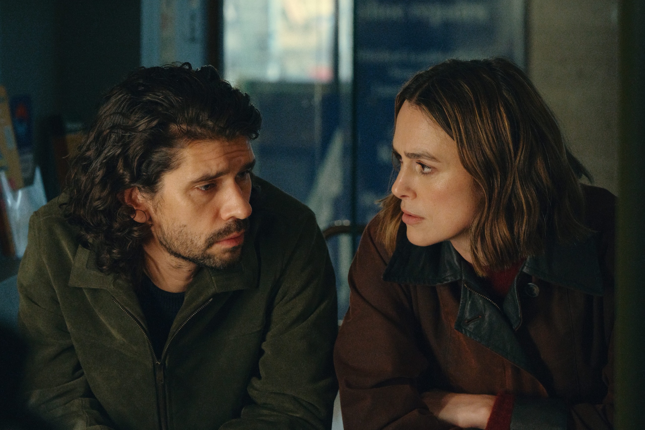 ben whishaw and keira knightley wearing coats and looking at one another while leaning over a balcony in black doves season 2