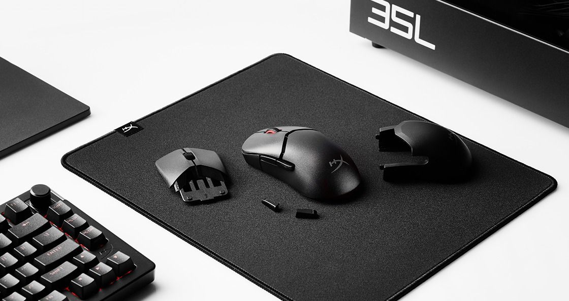 A HyperX Pulsefire Saga Pro gaming mouse on a desk with a mouse pad and spare parts