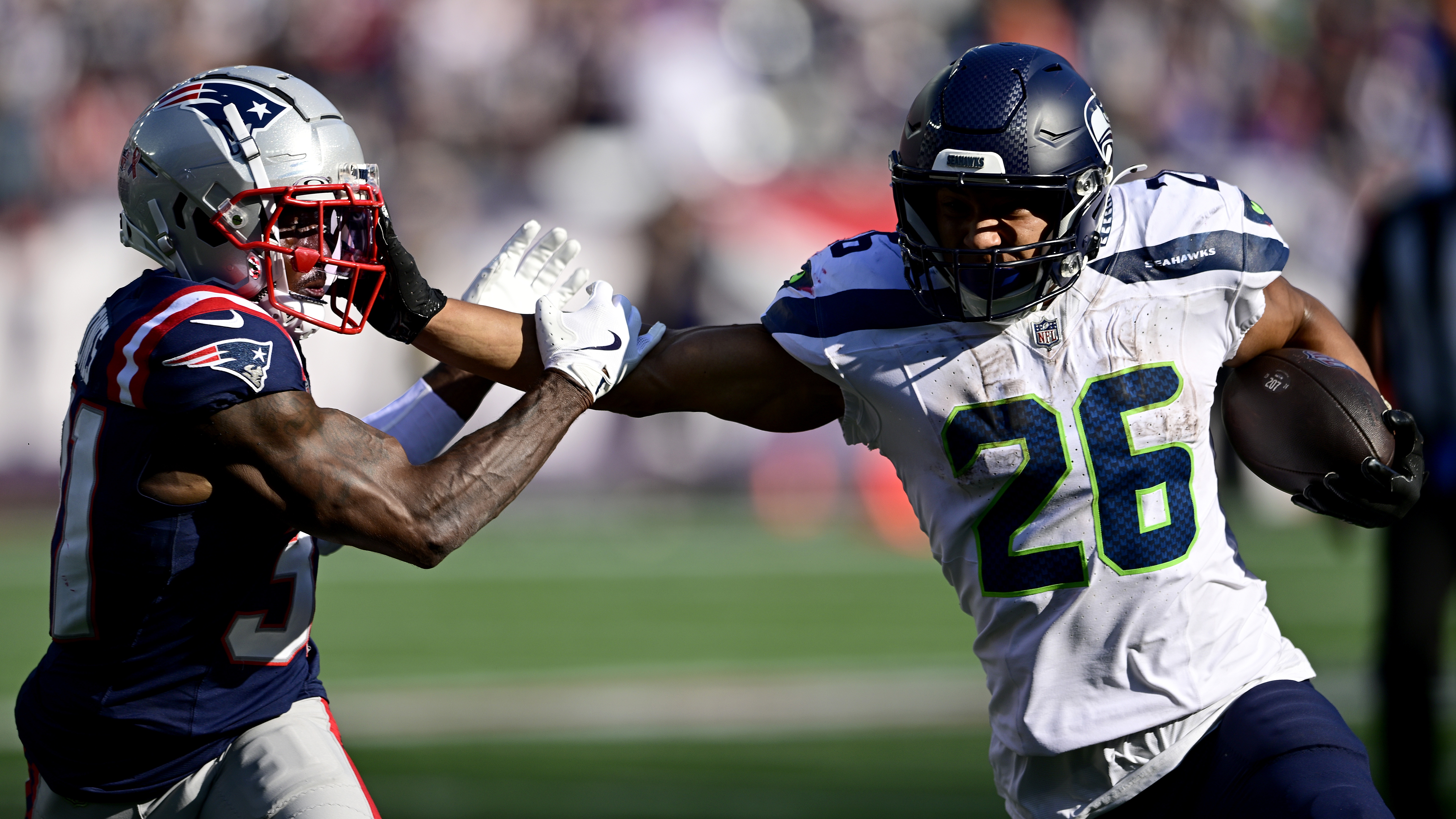 Zach Charbonnet #26 of the Seattle Seahawks runs with the ball against Jonathan Jones #31 of the New England Patriots during overtime at Gillette Stadium on September 15, 2024 in Foxborough, Massachusetts.