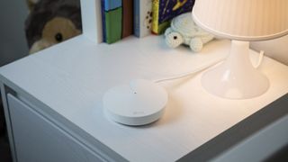 TP-Link Deco M5 node on a bedside table with soft warm lighting