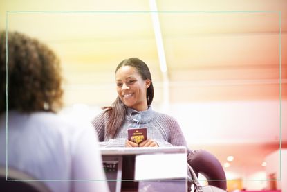 A woman holding her passport while standing at a check-in desk